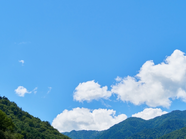 青空のもとに広がる緑豊かな山並みの風景
