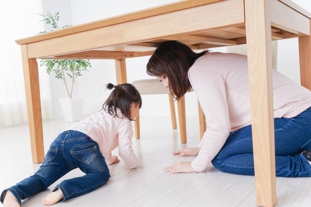 机の下に避難する親子