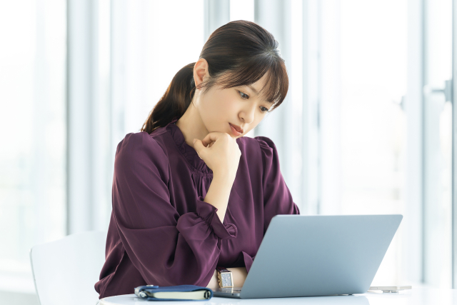 パソコンを使いながら考える女性