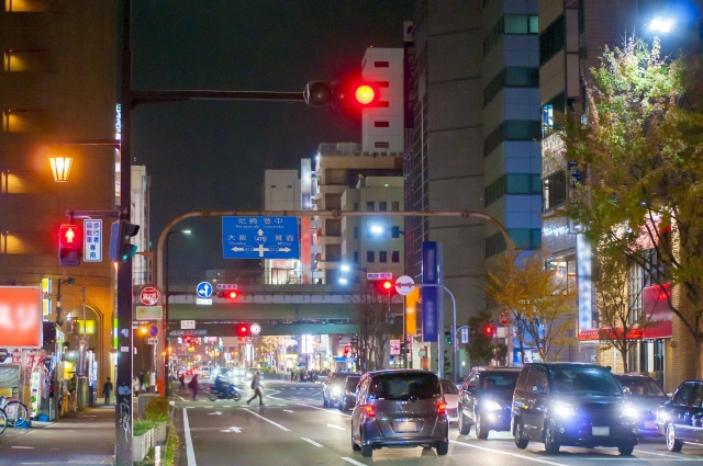 夜の街灯や車のヘッドライトで明るく照らされた大通りの風景
