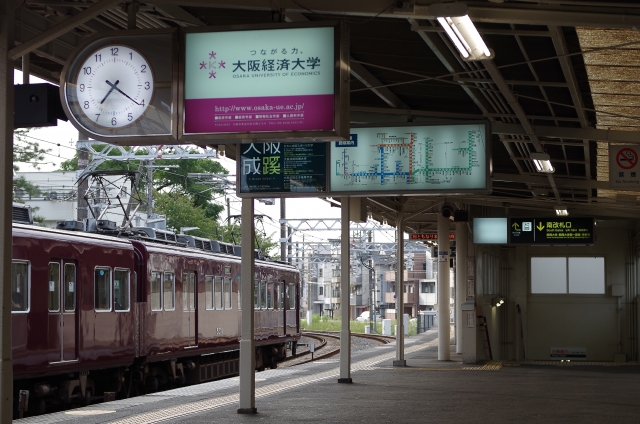 阪急電車の車両が停車している駅のホームと案内サインの風景
