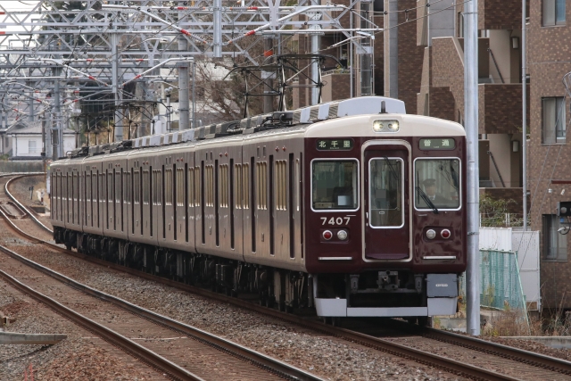 線路の上を走る阪急千里線のマルーン色の電車