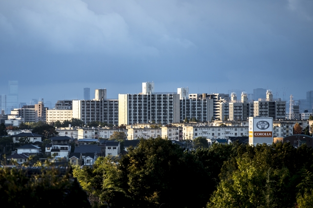 緑豊かな木々の向こうに広がる千里ニュータウンのマンション群と街並みのパノラマ風景

