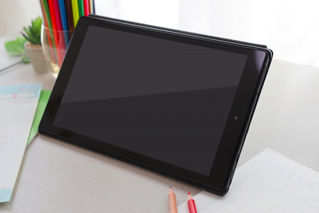 学習机の上に置かれたタブレット端末と色鉛筆
