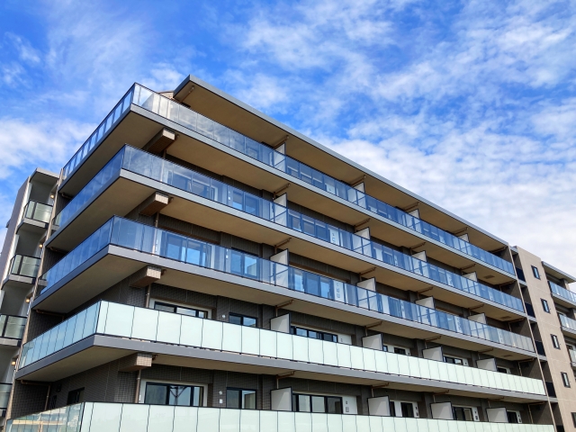 青空のもとに建つ近代的なマンションの外観
