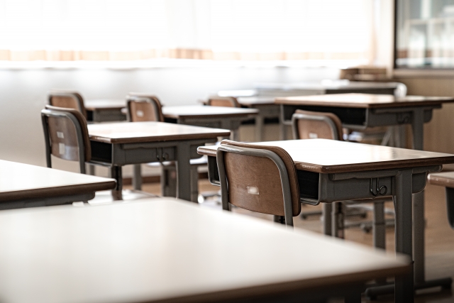 光が差し込む学校の教室と並べられた学習机
